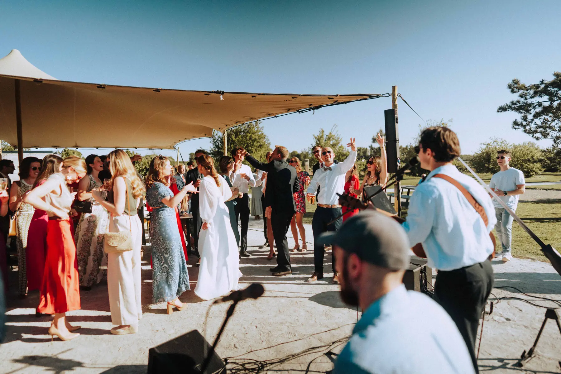 Les invités dansent devant JamBag lors d'un mariage en plein air