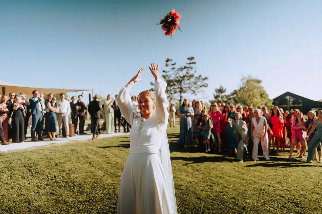 La mariée lance son bouquet devant ses invités