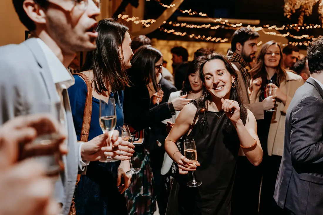 Une invitée chante, coupe de champagne à la main