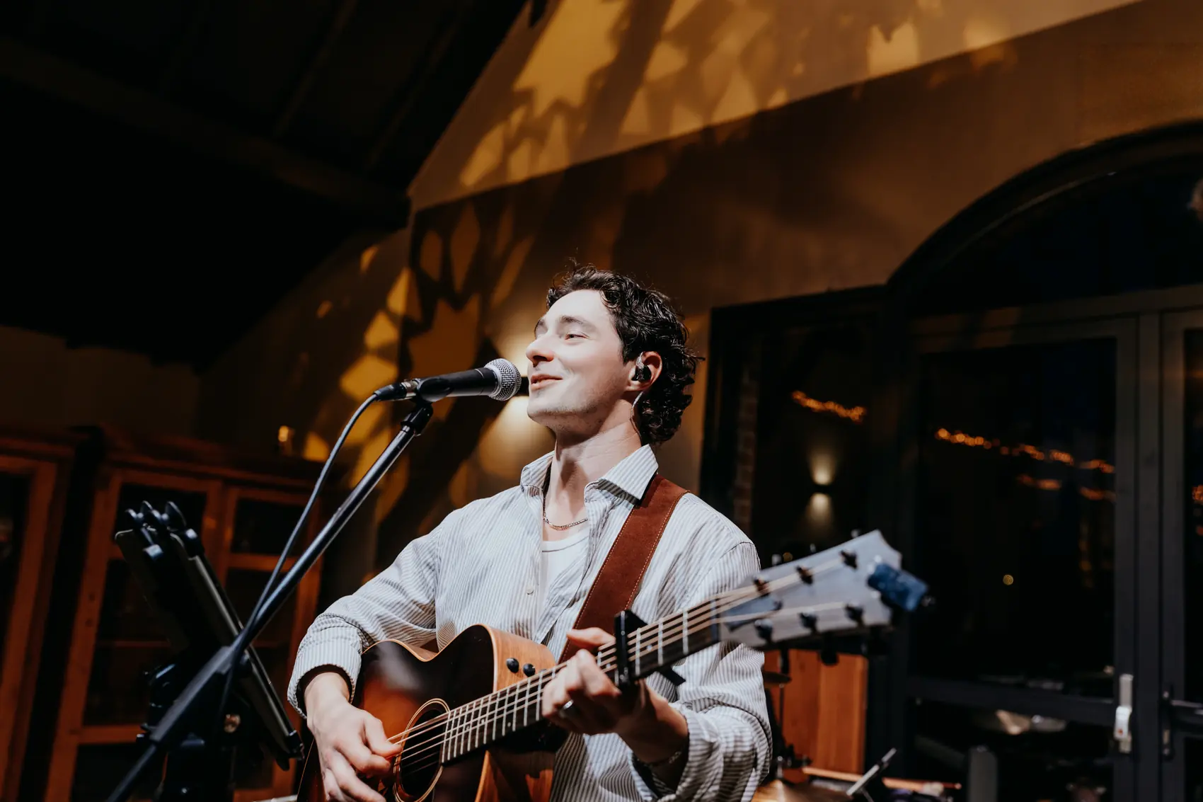 Carl seul à la guitare acoustique, sous une lumière chaude