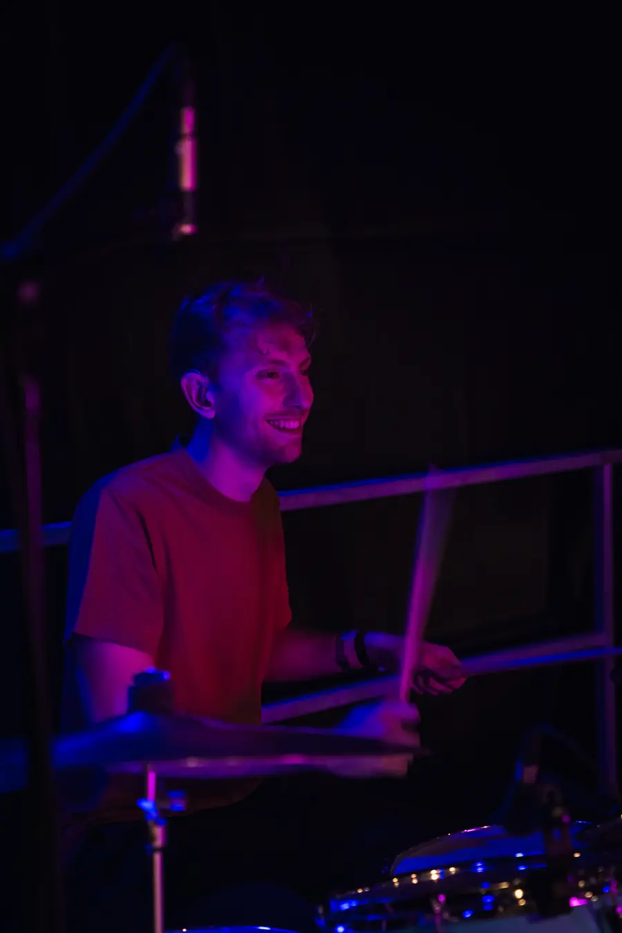 Timothée à la batterie sous une lumière violette