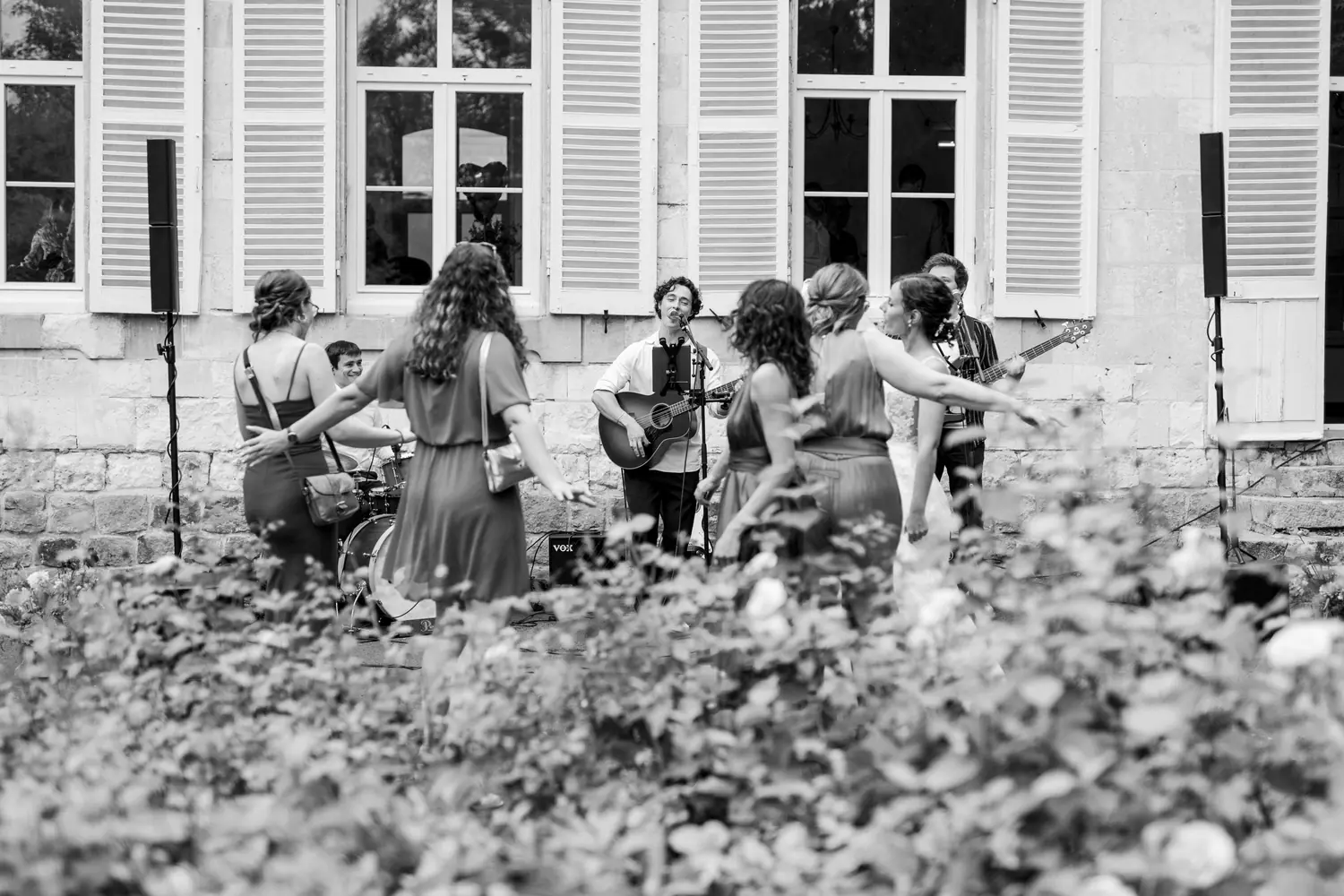 Les invitées dansent devant le trio, en noir et blanc